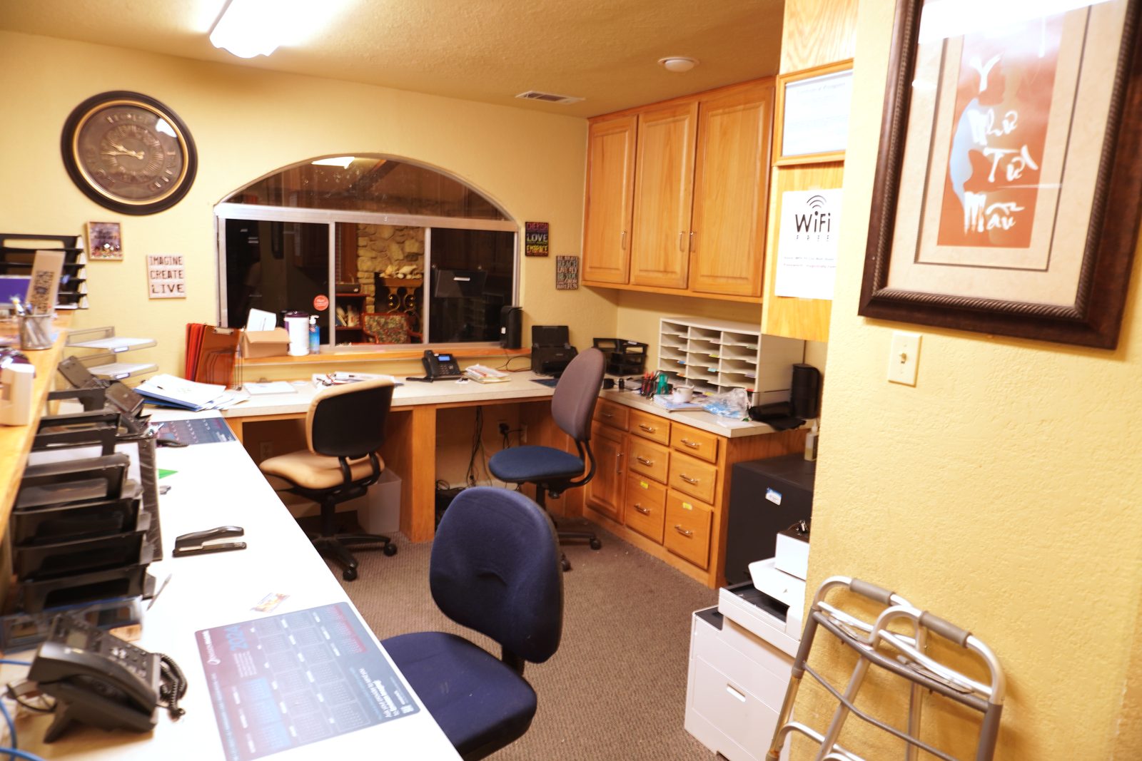 Front office reception counter seen from behind, with document organisers and an arched masonry pass-through window.