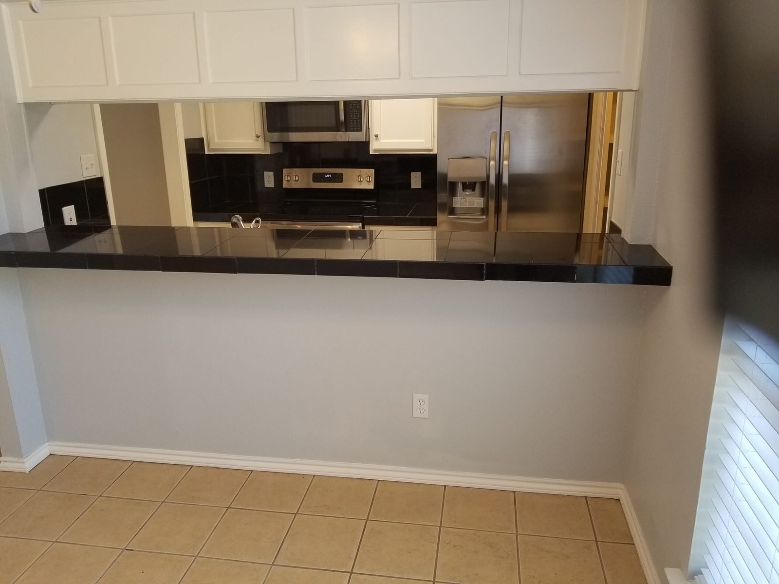 Breakfast bar pass-through with dark counter facing the kitchen
