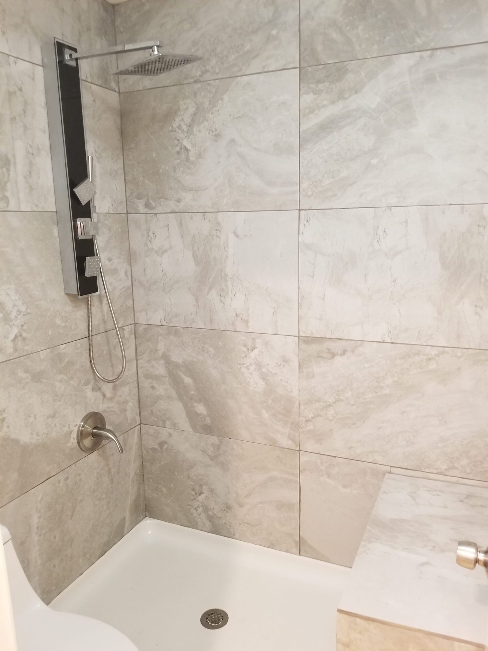 Walk-in spa shower with large-format stone-look tile, rain head and thermostatic control panel